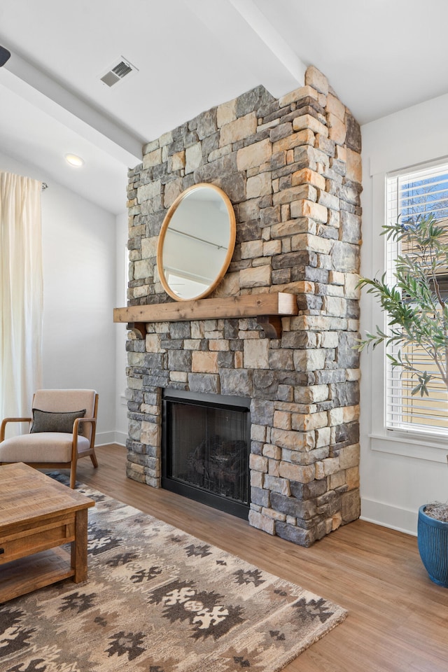 living area featuring lofted ceiling with beams, light wood-style floors, a fireplace, and baseboards