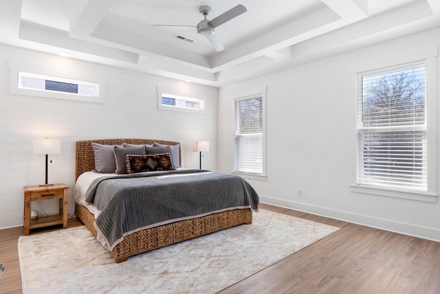 bedroom with coffered ceiling, multiple windows, baseboards, and wood finished floors