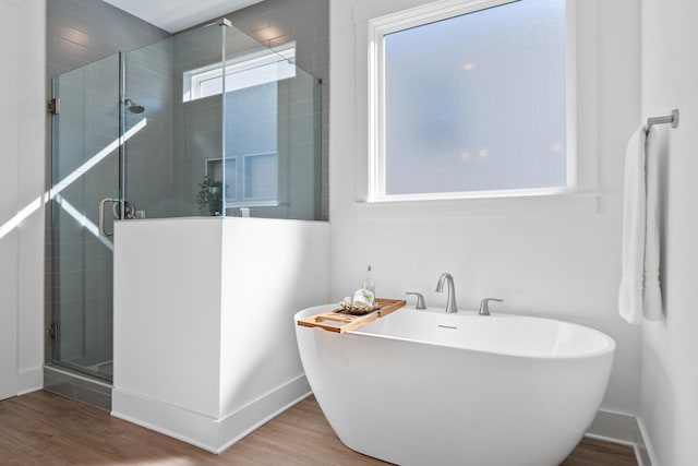 full bathroom with a freestanding bath, wood finished floors, a shower stall, and baseboards