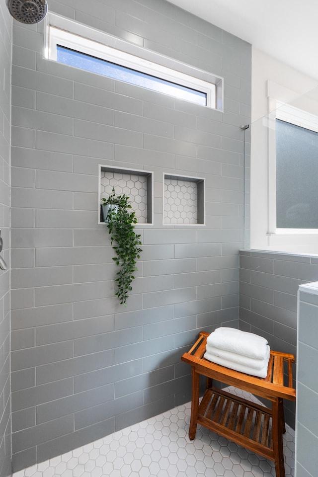 full bathroom featuring a healthy amount of sunlight, a tile shower, and tile walls