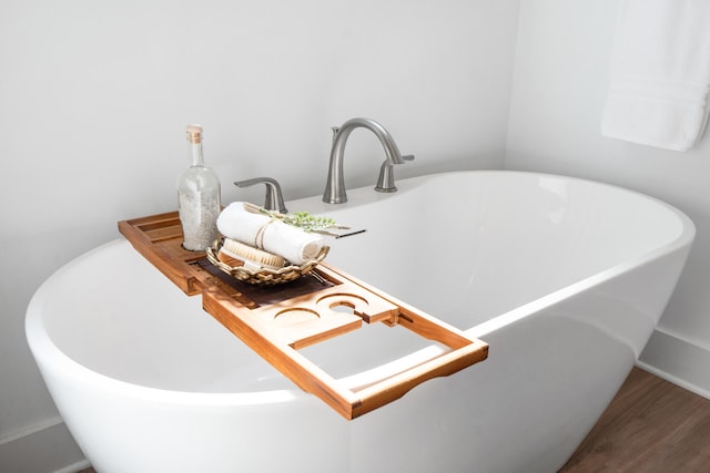 details with a freestanding tub and wood finished floors