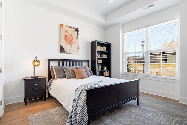 bedroom with wood finished floors, visible vents, and baseboards