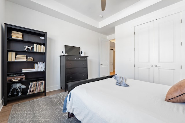 bedroom with dark wood-style floors, a closet, a ceiling fan, and baseboards