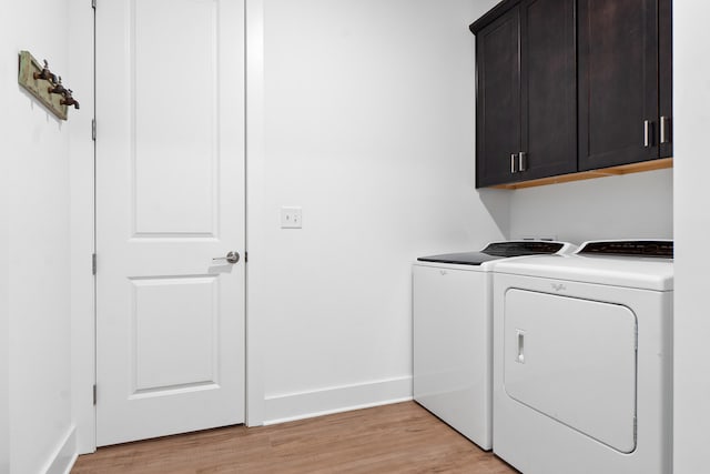 laundry area with baseboards, light wood-style flooring, cabinet space, and washer and dryer