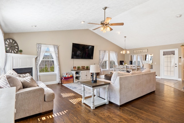 living area featuring dark wood-style floors, baseboards, vaulted ceiling, and a wealth of natural light