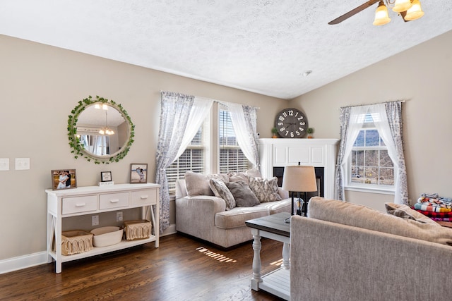 living room with ceiling fan, a textured ceiling, lofted ceiling, baseboards, and dark wood-style floors