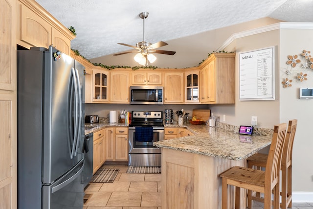 kitchen featuring glass insert cabinets, a peninsula, vaulted ceiling, stainless steel appliances, and light brown cabinetry