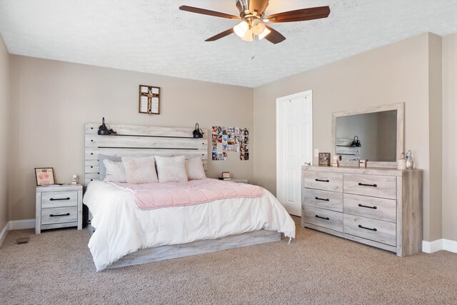 bedroom with a ceiling fan, light colored carpet, a textured ceiling, and baseboards