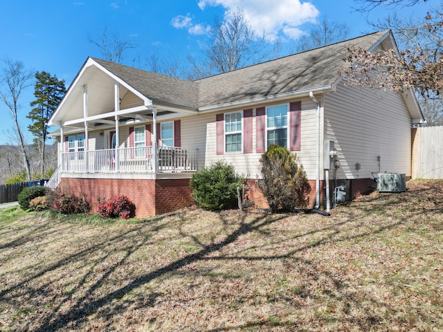 view of front of property with a shingled roof, a porch, central AC, and a front yard