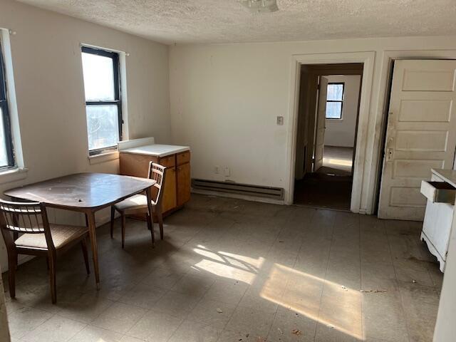 dining area with a baseboard radiator, a textured ceiling, and dark floors