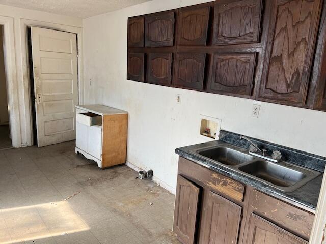 kitchen featuring dark countertops, light floors, a sink, and dark brown cabinets