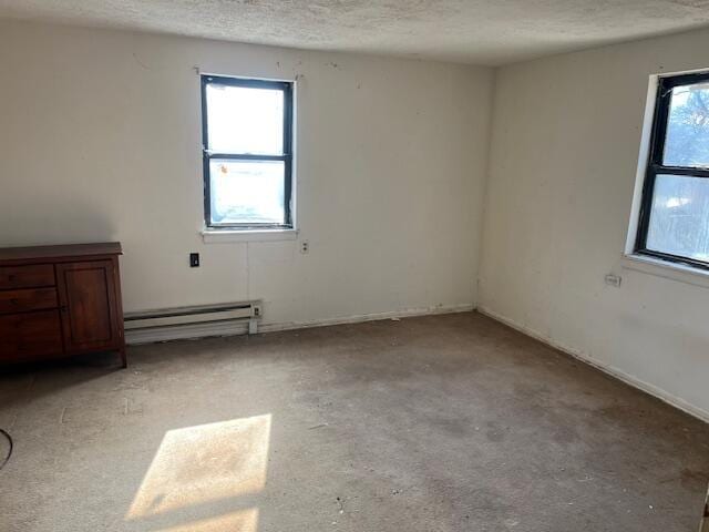 empty room with a baseboard heating unit, concrete flooring, and a textured ceiling