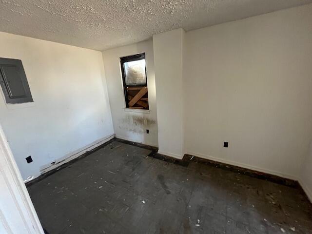 empty room with electric panel and a textured ceiling