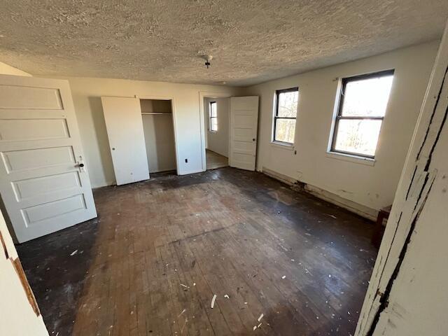 unfurnished bedroom with dark wood finished floors and a textured ceiling