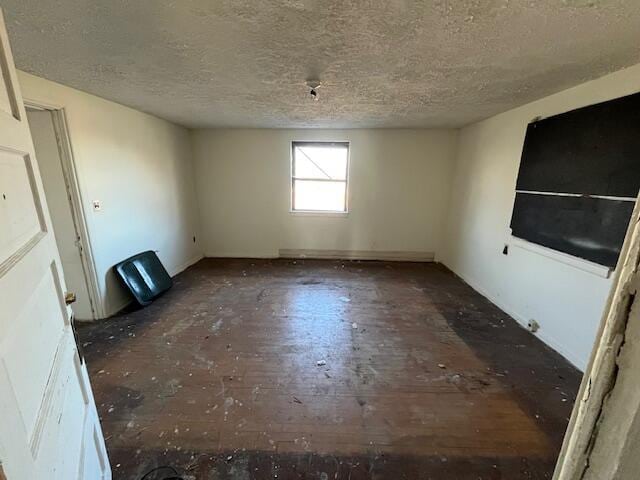 unfurnished room with dark wood finished floors and a textured ceiling