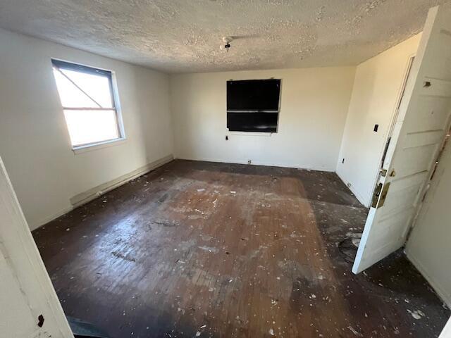 spare room featuring a textured ceiling and dark wood finished floors