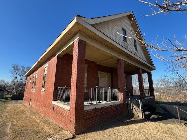 view of property exterior featuring covered porch and brick siding