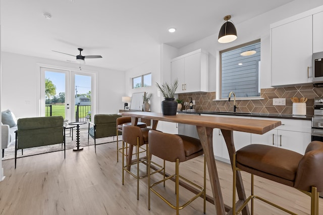 kitchen with pendant lighting, stainless steel appliances, butcher block counters, open floor plan, and white cabinetry