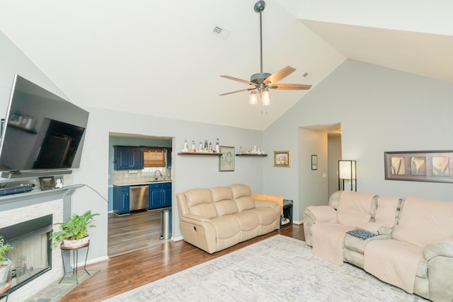 living room with a fireplace with flush hearth, visible vents, vaulted ceiling, and wood finished floors