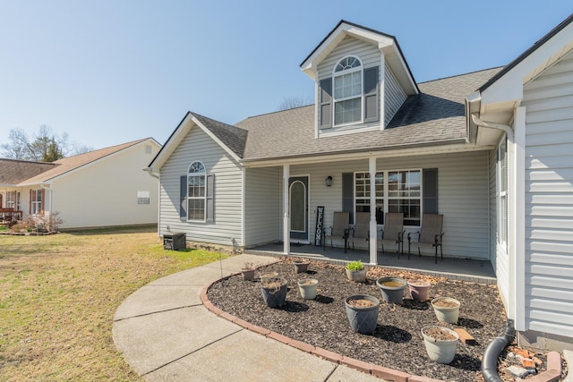 view of front of house featuring a shingled roof, a porch, and a front lawn