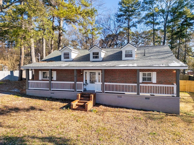 view of front of house featuring a porch, a front yard, brick siding, and fence