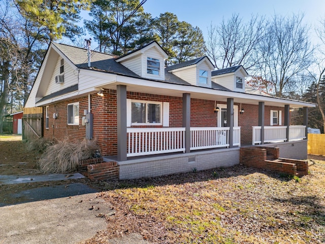 new england style home featuring a porch and brick siding