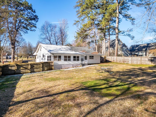 back of house with entry steps, a lawn, and fence