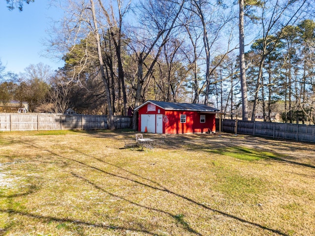 view of yard featuring a garage, a fenced backyard, an outdoor structure, and a storage shed