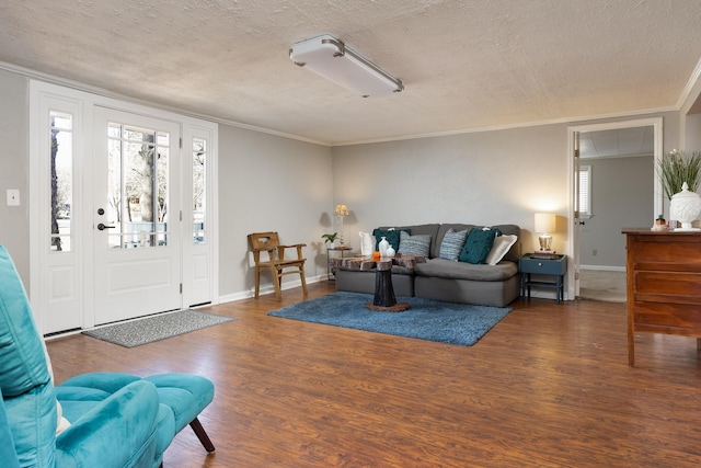 living area with ornamental molding, a textured ceiling, baseboards, and wood finished floors