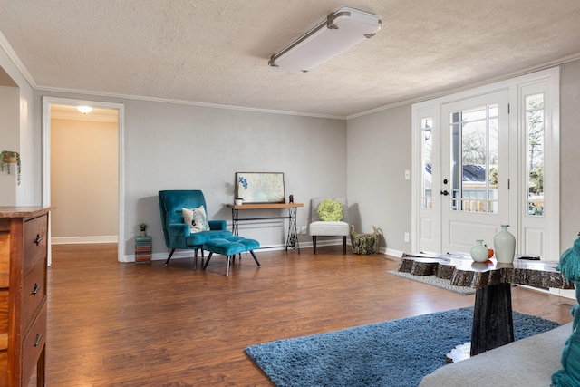 sitting room with ornamental molding, a textured ceiling, baseboards, and wood finished floors