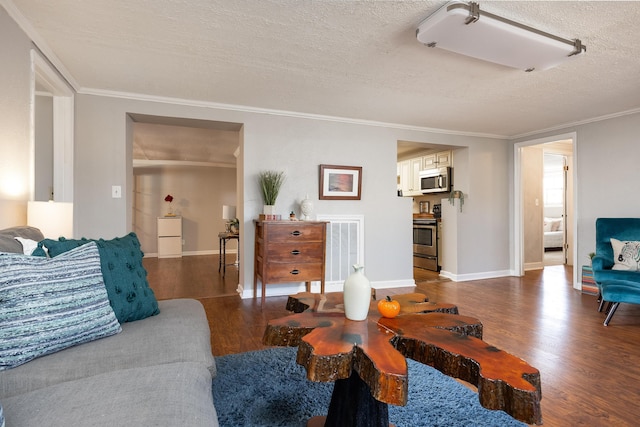 living room featuring visible vents, a textured ceiling, ornamental molding, and wood finished floors