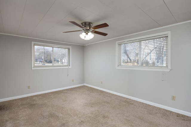 carpeted empty room with baseboards, a ceiling fan, and crown molding