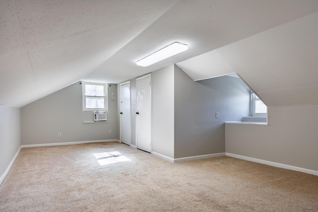 bonus room with a wealth of natural light, carpet flooring, a textured ceiling, and baseboards