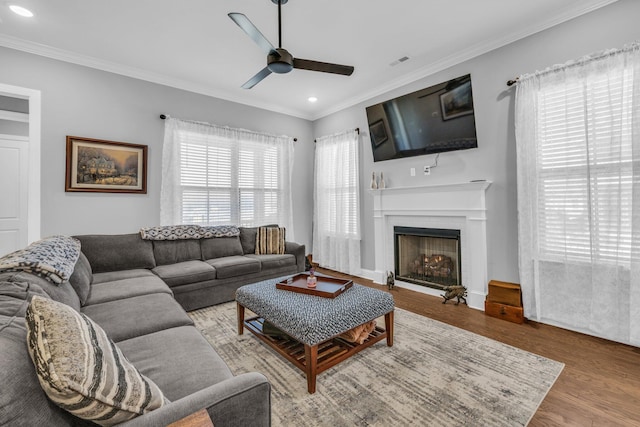 living room with ornamental molding, a fireplace, wood finished floors, and visible vents