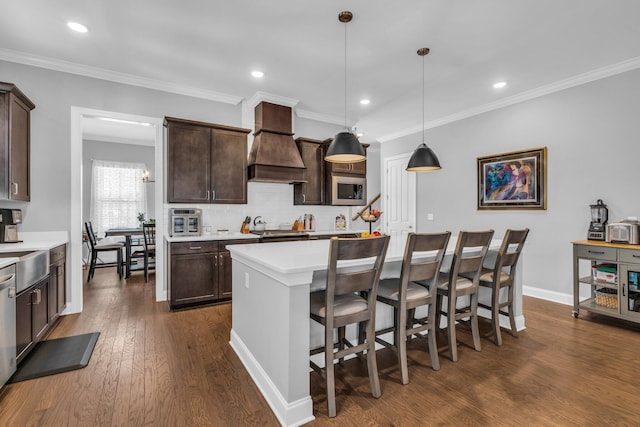 kitchen with appliances with stainless steel finishes, light countertops, premium range hood, and dark brown cabinets