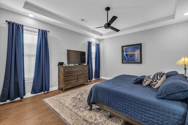 bedroom featuring a raised ceiling, baseboards, and wood finished floors