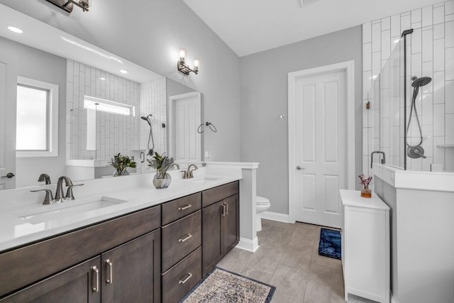 bathroom featuring a sink, a tile shower, and double vanity