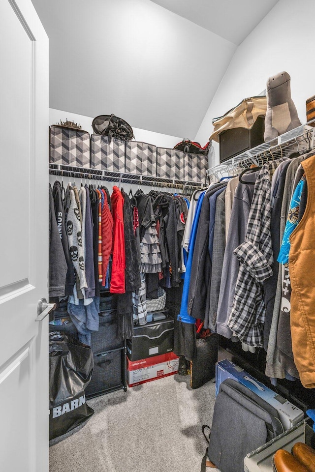 walk in closet with vaulted ceiling and carpet flooring