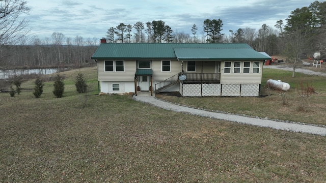 view of front of home with a chimney, metal roof, and a front yard