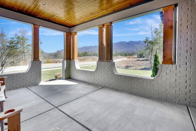 unfurnished sunroom with wood ceiling and a mountain view