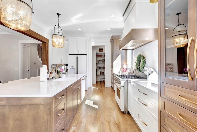 kitchen with premium appliances, light countertops, light wood-style flooring, white cabinets, and an island with sink