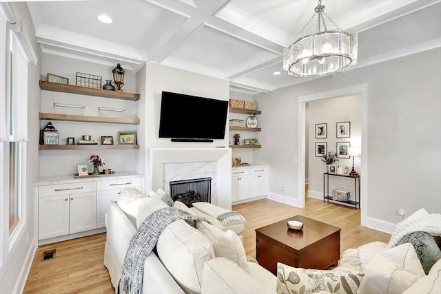 living room featuring beam ceiling, a fireplace, light wood finished floors, visible vents, and coffered ceiling