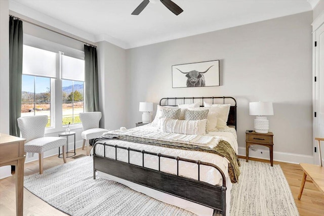 bedroom featuring a ceiling fan, light wood-style flooring, and baseboards