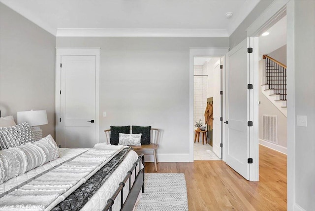 bedroom with light wood-type flooring, baseboards, visible vents, and ornamental molding