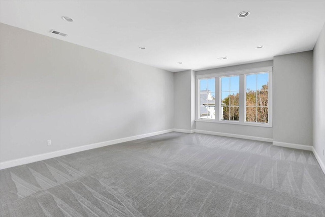 spare room with light carpet, recessed lighting, visible vents, and baseboards