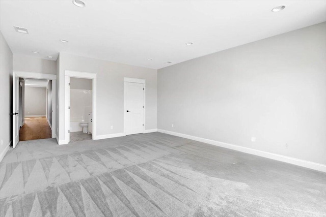 unfurnished bedroom featuring light colored carpet, connected bathroom, visible vents, and baseboards