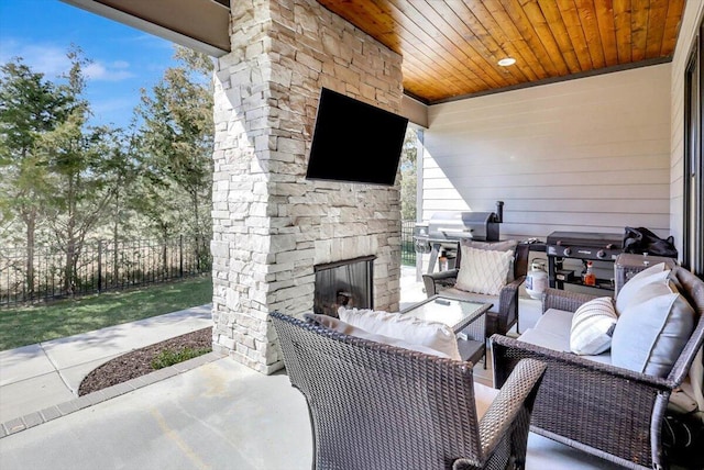 view of patio / terrace featuring fence, an outdoor stone fireplace, and grilling area