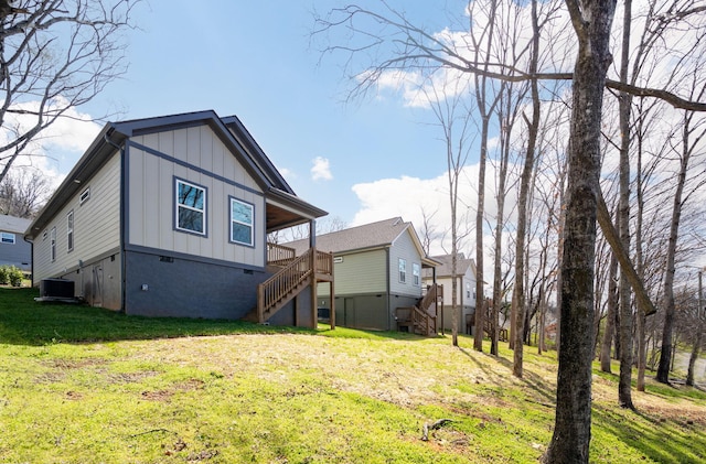 rear view of property featuring a yard, central AC unit, board and batten siding, and stairs