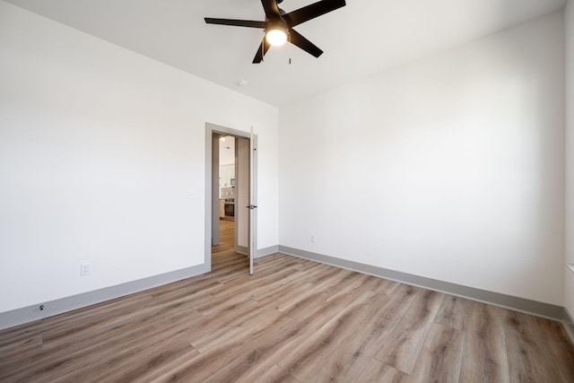 spare room with light wood-style flooring, a ceiling fan, and baseboards