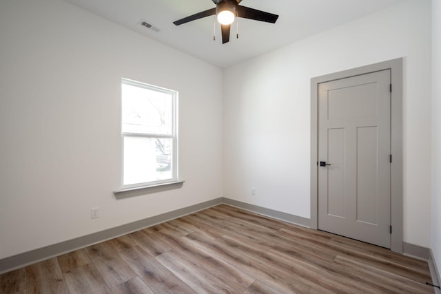 empty room featuring light wood-style flooring, baseboards, visible vents, and ceiling fan